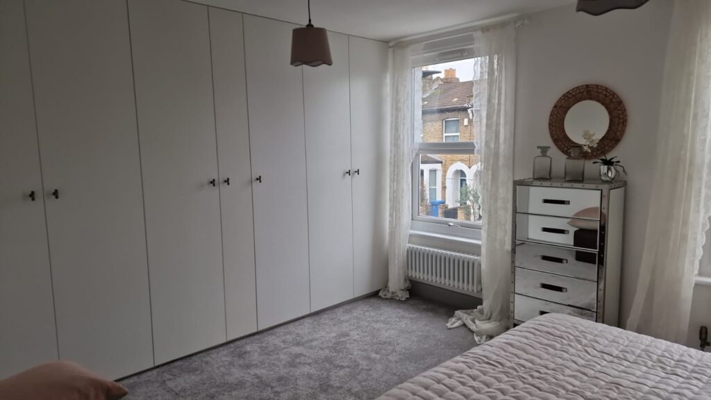 Living Room & Bedroom Renovation | London & Home Counties 1 Interior view of a modern bedroom featuring a white wardrobe and a mirrored chest of drawers. - London