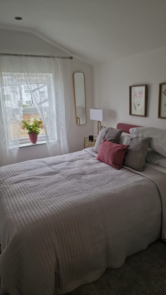 Living Room & Bedroom Renovation | London & Home Counties 3 A modern bedroom featuring a bed with decorative pillows and a window with sheer curtains. - London