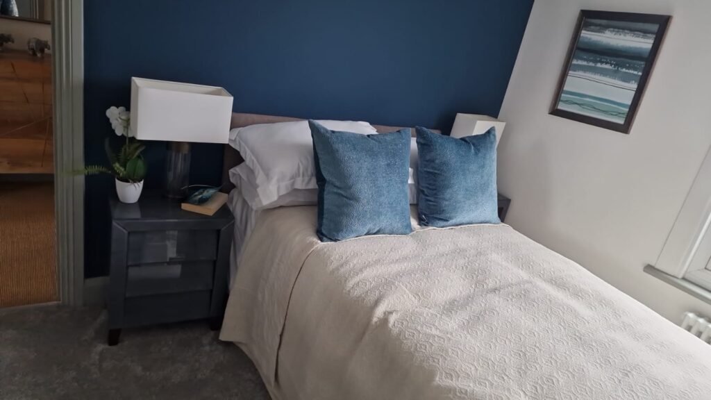Living Room & Bedroom Renovation | London & Home Counties 8 Single bed with blue cushions, a nightstand, and a lamp in a room with a blue wall. - London