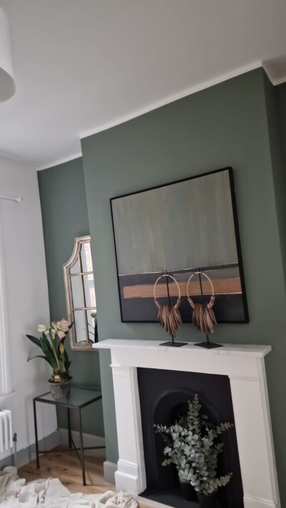 Living Room & Bedroom Renovation | London & Home Counties 9 Abstract artwork displayed on a green wall above a white fireplace with decorative objects. - London