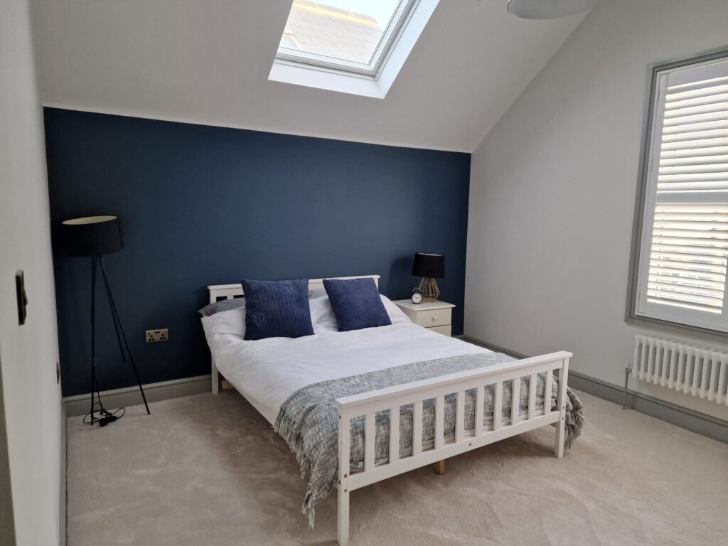 Living Room & Bedroom Renovation | London & Home Counties 13 A bedroom featuring a white bed with blue accent pillows against a blue wall. - London