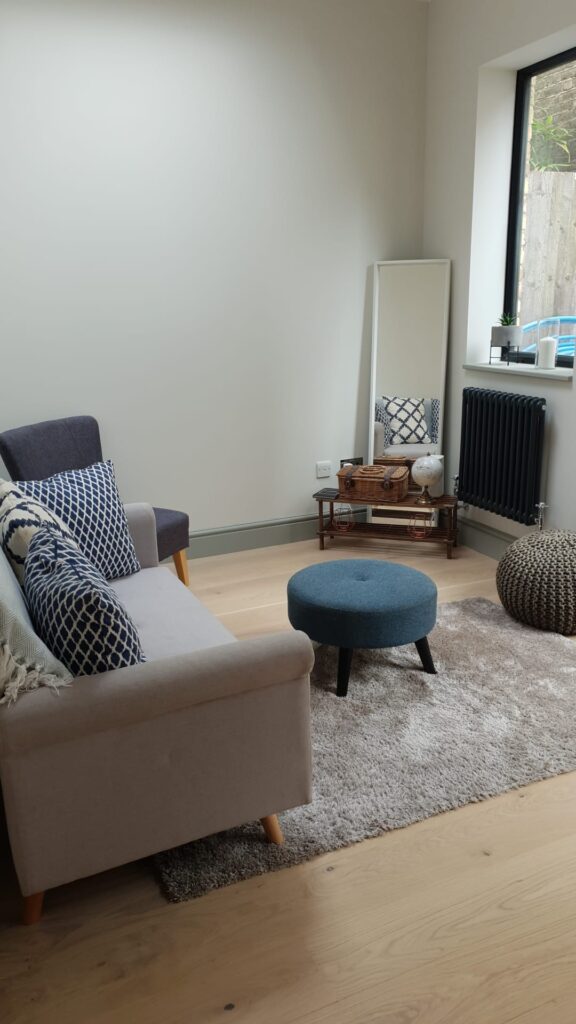 Living Room & Bedroom Renovation | London & Home Counties 22 A living room featuring a grey sofa, blue ottoman, and a large mirror against a wall. - London