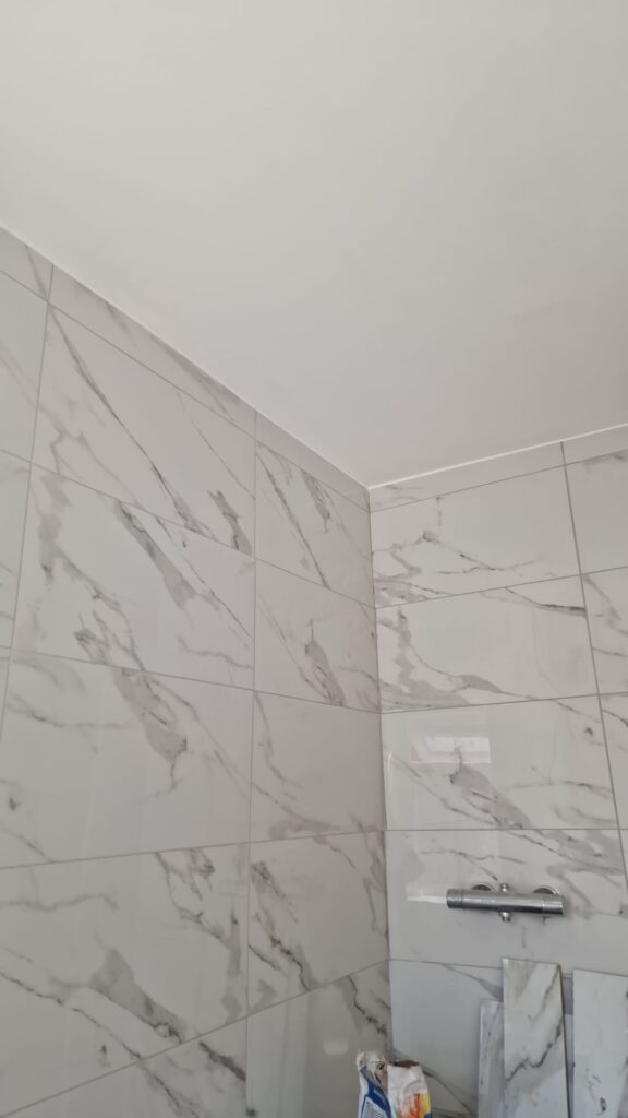 Close-up of marble effect wall tiles in a bathroom setting, featuring grey and white patterns. - London