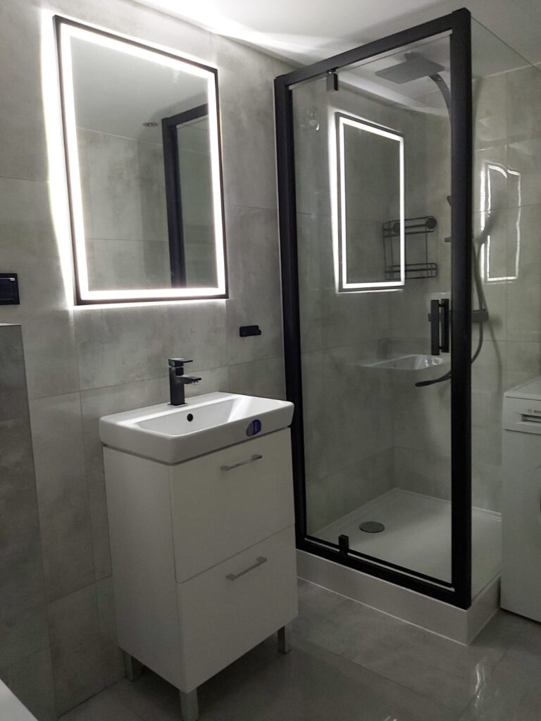 Contemporary bathroom featuring a shower cubicle and a white vanity unit with a mirror. - London