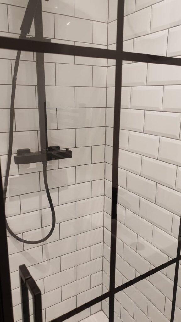 Shower enclosure featuring black fixtures and white subway tiles in a modern design. - London