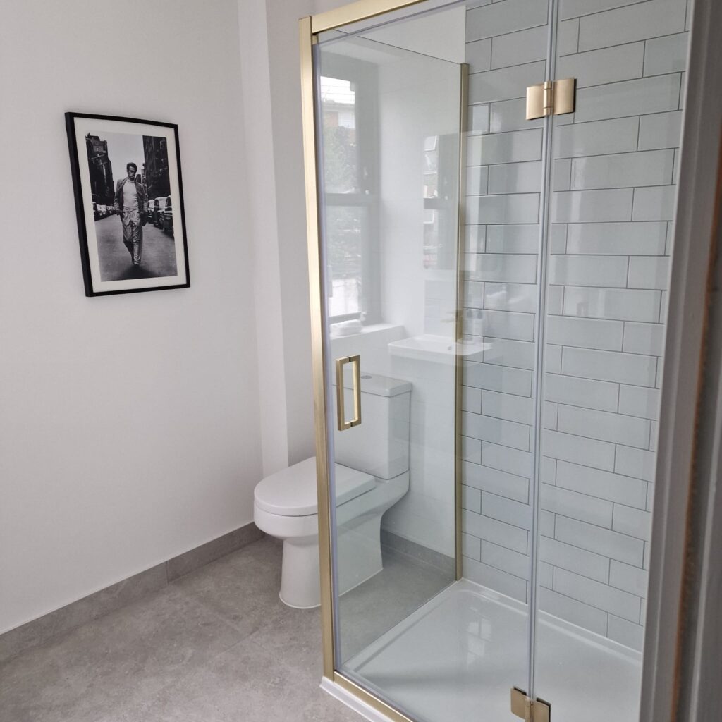 A modern bathroom featuring a glass shower enclosure and a white toilet. - London