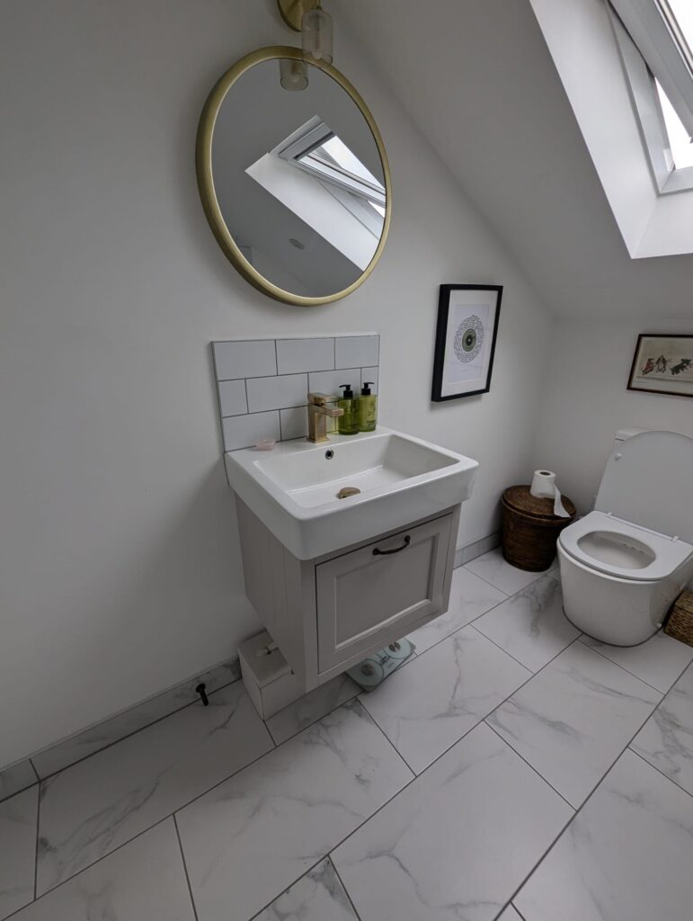A modern bathroom sink with a round mirror above it, featuring toiletries on the counter. - London