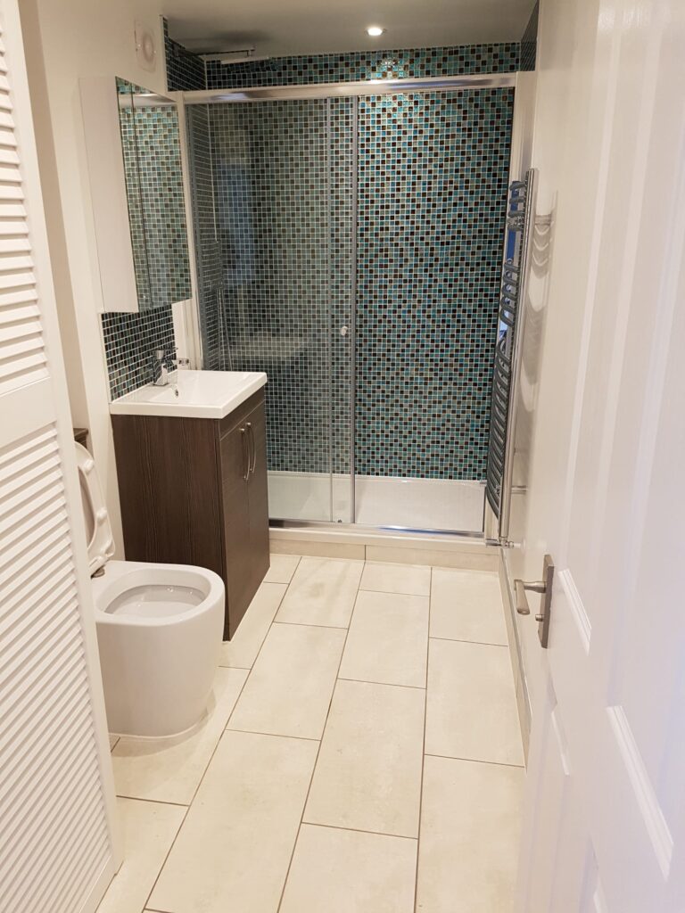 Interior view of a modern bathroom featuring a shower, vanity unit, and toilet. - London