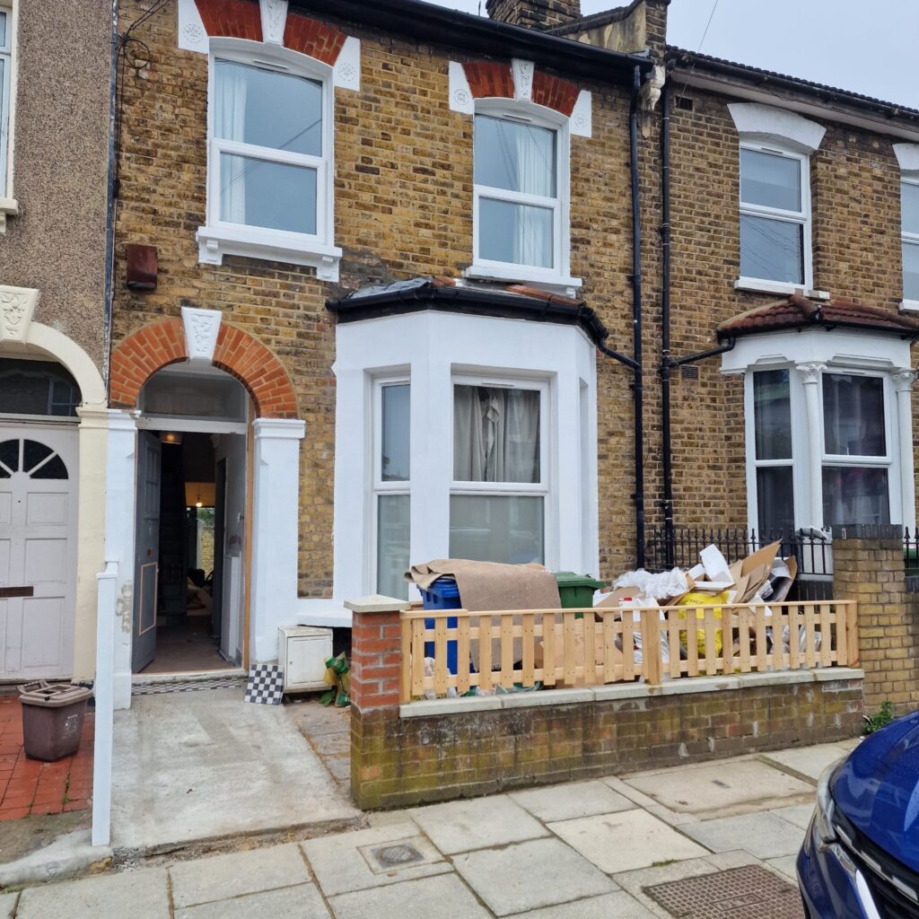 Garden Buildings & Outdoor Spaces | London & Home Counties 22 Front view of a renovated brick terraced house with a wooden fence and construction materials outside. - London