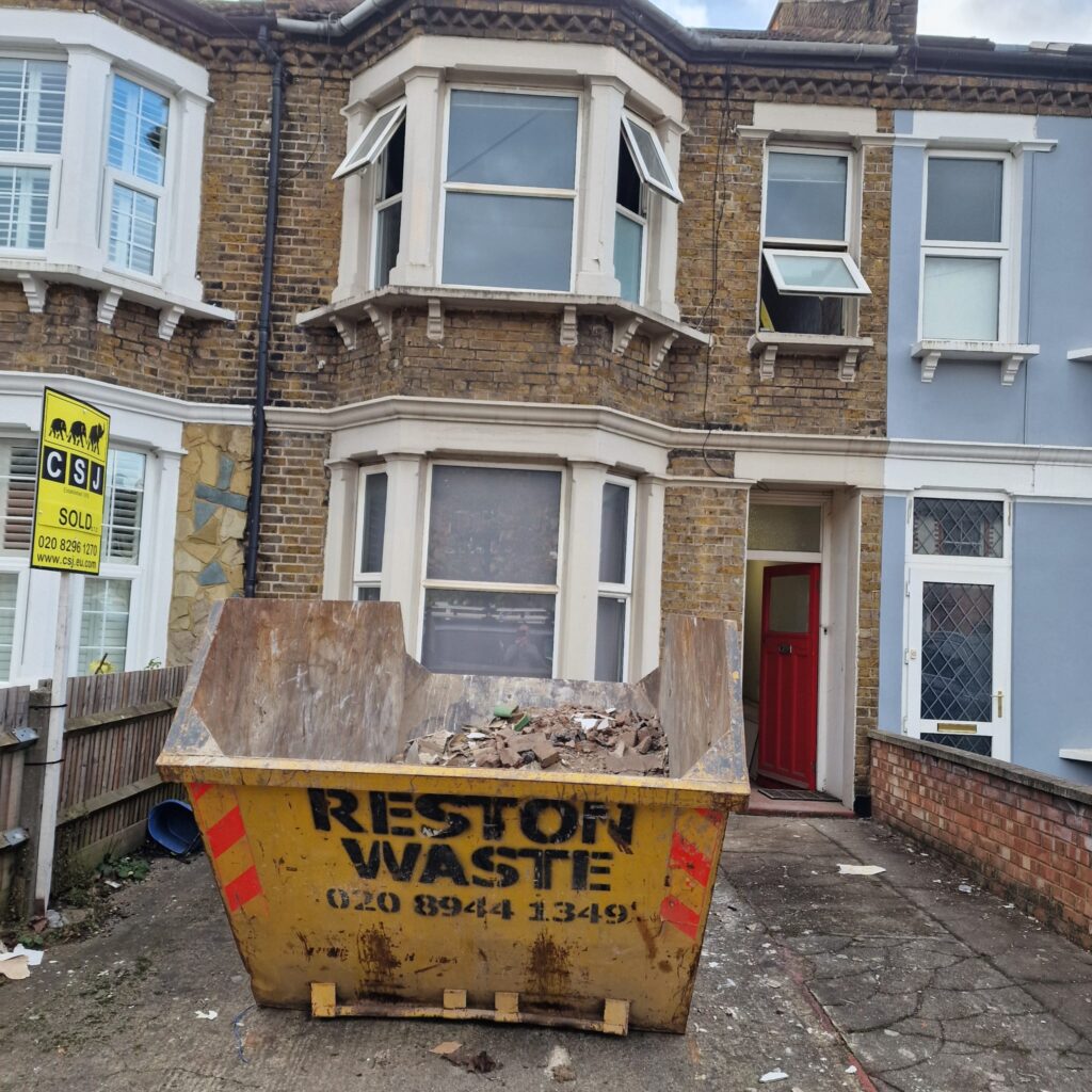 Garden Buildings & Outdoor Spaces | London & Home Counties 23 Large skip bin labelled 'RESTON WASTE' filled with debris outside a residential building. - London