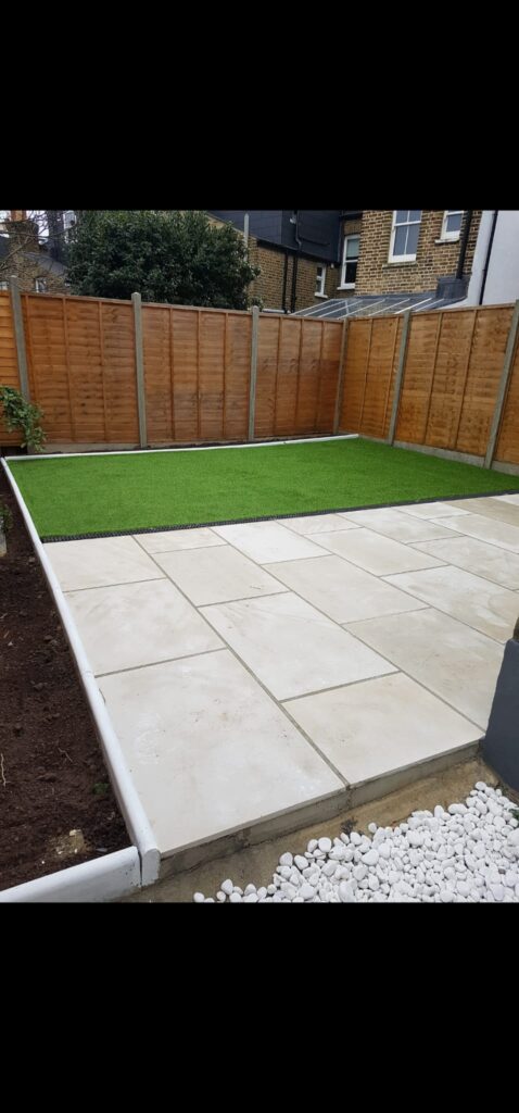 Garden Buildings & Outdoor Spaces | London & Home Counties 24 A garden area featuring a paved section and artificial grass surrounded by wooden fencing. - London