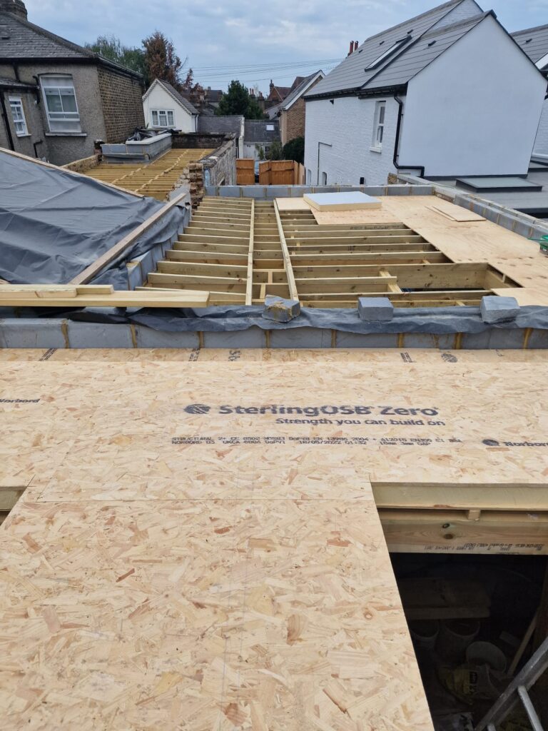 View of a roof under construction with wooden beams and OSB boards laid out.