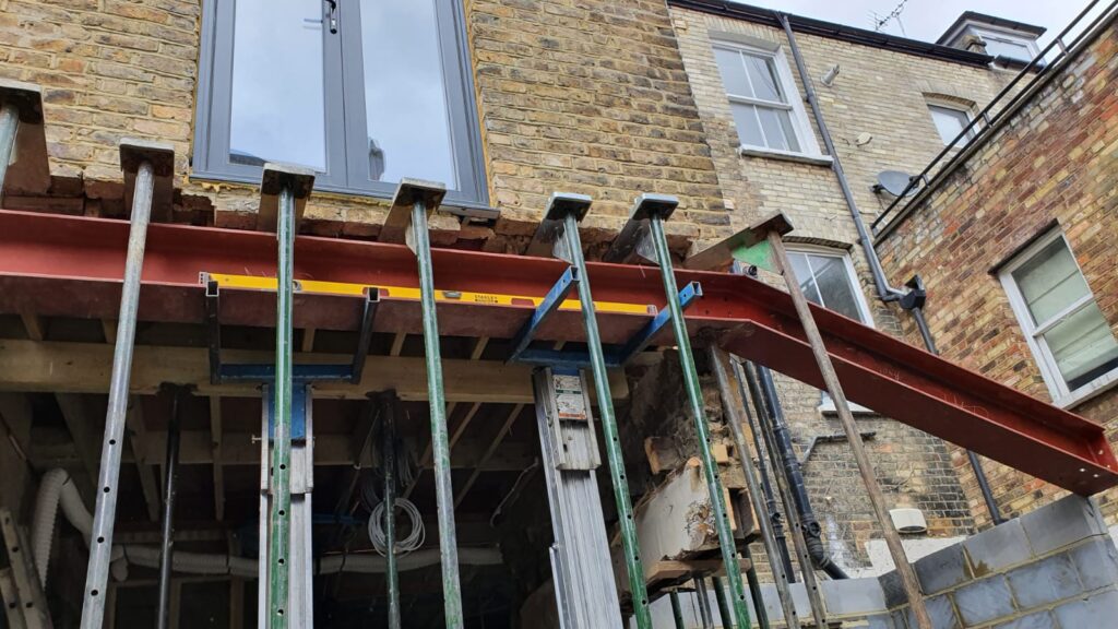 House Extensions | London & Home Counties | 30+ Years Experience 4 Steel beam structure supported by props during construction phase of a building.