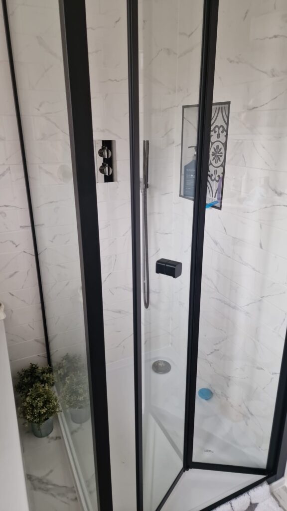 A modern shower enclosure featuring glass panels and a chrome showerhead. - London