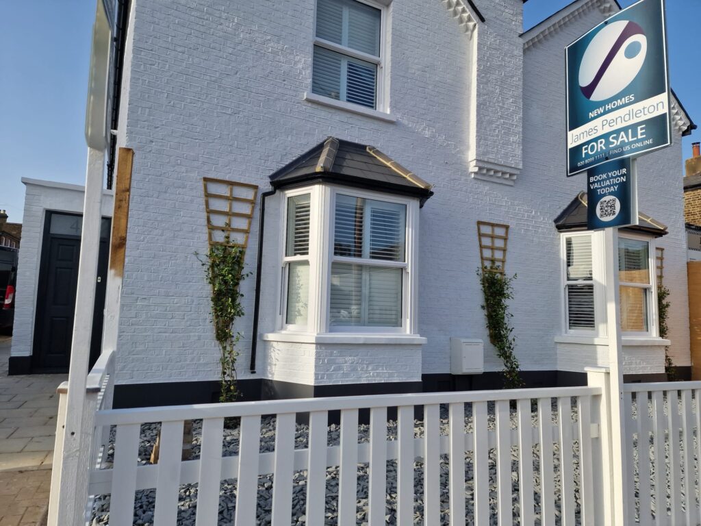 Garden Buildings & Outdoor Spaces | London & Home Counties 33 Exterior view of a white house featuring bay windows and a for sale sign in front.