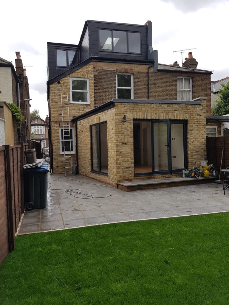 House Extensions | London & Home Counties | 30+ Years Experience 1 A modern brick house extension featuring large glass doors and a patio area.